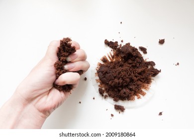 Hand Crushing A Chocolate Muffin In A Fist Against A White Background. Top Down View Of Crumbs And Mess.