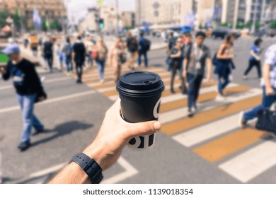 A Hand With A Cup Of Coffee On The Background Of A Big Noisy Street Or Intersection In A City In Summer In Sunny Clear Weather