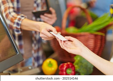 Hand Of Customer Giving Credit Card To Supermarket Cashier At Checkout