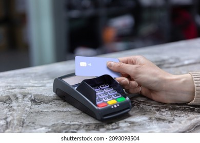 Hand of customer paying with contactless credit card with NFC technology. Bartender with a credit card reader machine at bar counter with female holding credit card. Focus on hands.