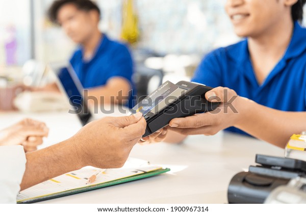 Hand of customer using credit card for payment at\
the auto car repair shop. Pay by credit card. Pay online with\
credit card