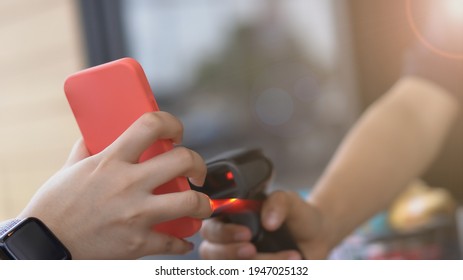 Hand Of Customers In The Car Using Mobile Phone Pay For Food Or Drinks. Salesperson Is Using A Barcode Reader To Accept Payment. Driving Through Or Drive Thru Concept.