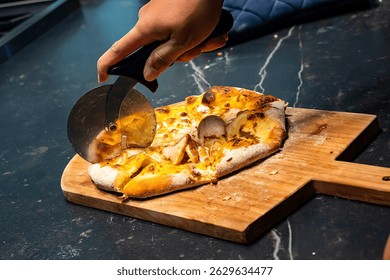 Hand Cutting Cheese Pizza Using a Pizza Cutter on a Wooden Board