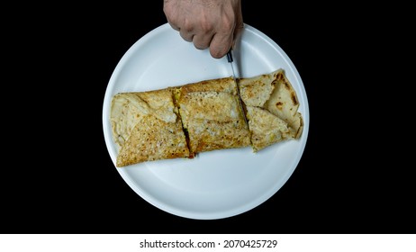 Hand Cutting Dosa With Knife In White Plate, Three Piece Of Dosa, Isolated In Black Background