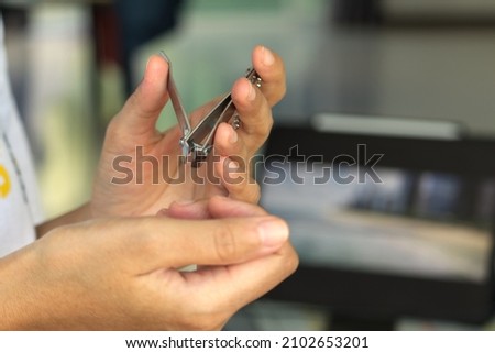 Hand cutting nails using nail clipper - close up , foot finger on fabric