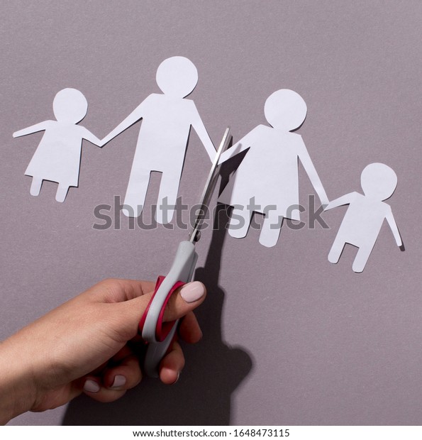 Hand Cutting paper family, the inscription\
divorce. Concept of breaking relations, quarrels, treachery,\
betrayal on gray\
background
