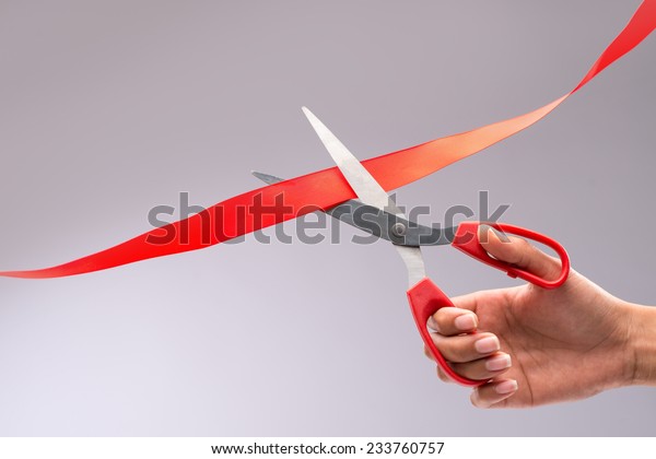 Hand cutting red\
ribbon