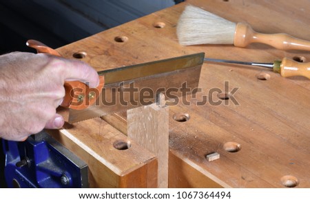 Hand cutting or sawing mortise and tenon woodworking joinery with a dovetail saw.  Oak board held by hard maple workbench vise.