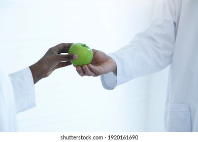 Hand Of The Dark Skinned Student Gave A Green Apple To The Science Teacher 