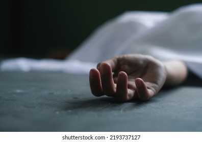 Hand of dead victim woman covered by white cloth,horror and crime scene.