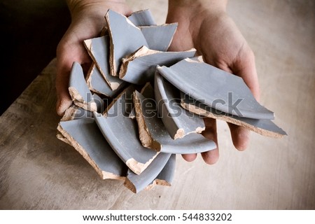 In hand debris or smithereens. Ware splinters in hands closeup. Caucasian man holds in the hands of the debris or fragments of pottery broken plate