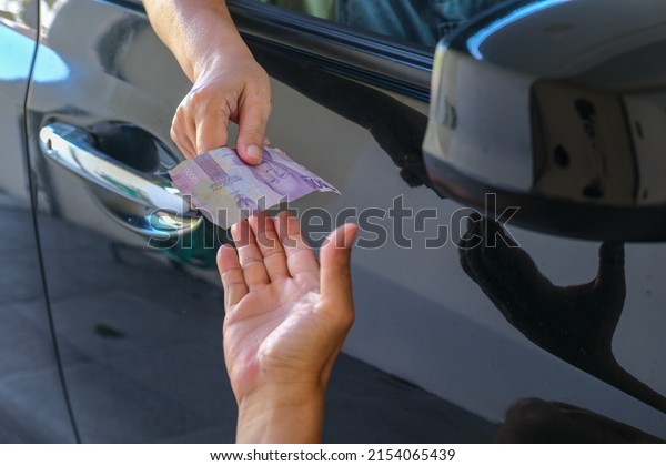 Hand\
delivering some money from outside car\
window