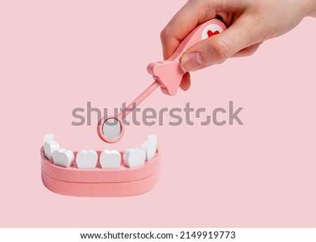 Hand with dental mirror teeth in jaw model and exploring patient oral cavity. Children game at dentist. Health care, stomatology concept. High quality photo