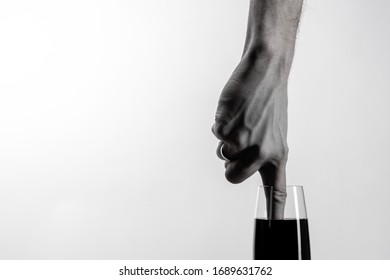 The hand dips its index finger into glass black liquid  Minimalism  Black   white photo  Copy space