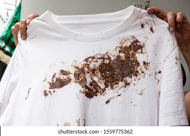 Hand With Dirty Shirt, Children Shirt With Chocolate Stains.