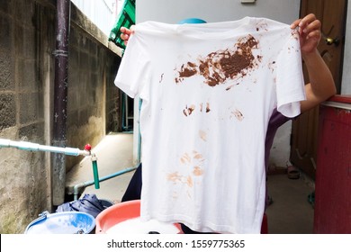 Hand With Dirty Shirt, Children Shirt With Chocolate Stains.