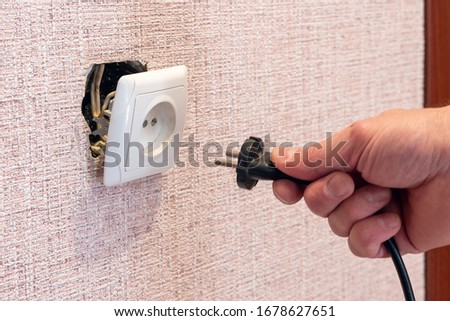 Hand disconnects or connects the plug to a broken outlet, risk of electric shock.