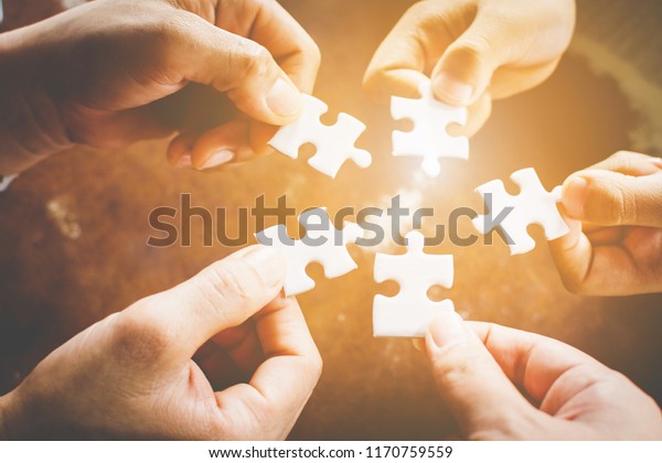Hand of diverse people\
connecting jigsaw puzzle. Concept of partnership and teamwork in\
business