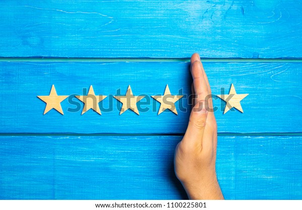The hand divides the fifth star from the four
others. Rating 5 stars, 4 stars. Overview of restaurant, hotel,
cafe. The deterioration of the rating, the loss of the fifth star.
Quality . Wooden stars