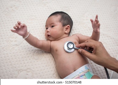 Hand doctor exams  baby with stethoscope,Pediatrician examines two months newborn asian girl,Doctor using a stethoscope to listen to child baby chest checking heartbeat 