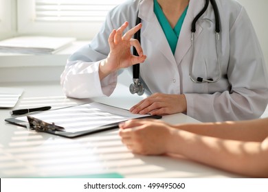 Hand of doctor  reassuring her female patient and showing ok sign. Medical ethics and trust concept