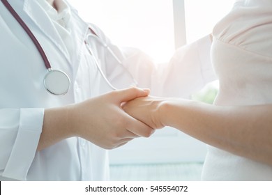 Hand der Ärztin, die ihre weibliche Patientin beruhigt.