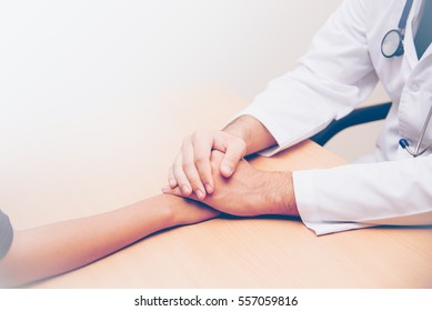 Hand of doctor reassuring her female patient on table.