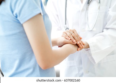 Hand der Ärztin, die ihre weibliche Patientin beruhigt
