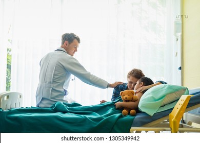 Hand of doctor reassuring Patient family with child patient on hospital bed at the Patient room in hospital / Teddy bear is a best friend for all little cute girl - Medical healthcare concept.  - Powered by Shutterstock