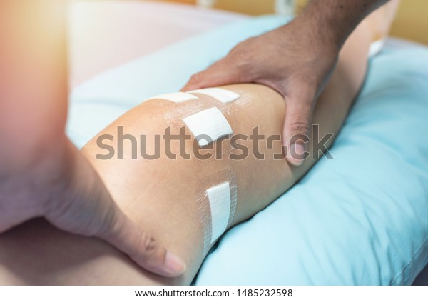 Hand of\
doctor touch on leg of patient after do ligament surgery on bed in\
hospital,healthcare and medical concept.\

