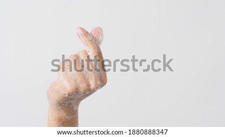 Hand doing mini heart or small heart hand sign and have foam soap bubbles on a white isolated background