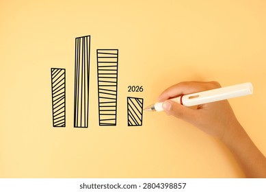 Hand drawing a bar chart with a declining 2026 value on a pastel background. Concept of business slowdown, revenue decline, economic challenges and financial performance.