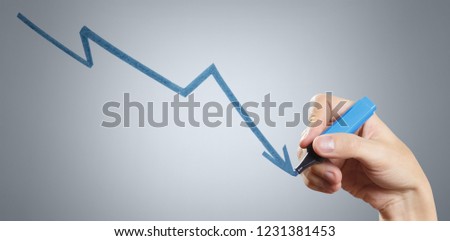 Hand drawing a decreasing graph using a blue marker on grey background