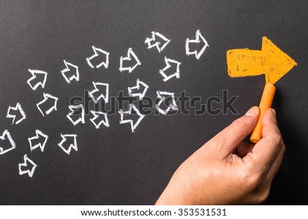 Hand drawing orange arrow as trend leader with many white arrows as follower