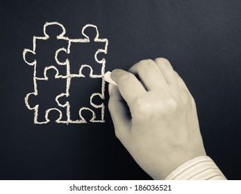 Hand drawing puzzle on blackboard to explain business concept - Shutterstock ID 186036521
