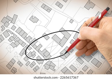 Hand drawing and select an area above an imaginary cadastral map of territory with buildings, fields, roads and land parcel - concept image