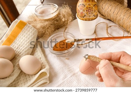 Hand drawing wax pattern on chicken egg for Easter decoration