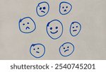 Hand drawn happy smiley face on white board surrounded by sad unhappy faces. Positive attitude or optimism concept.