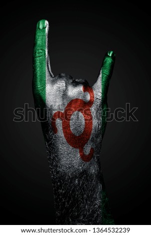 A hand with a drawn Ingushetia flag shows a goat sign on a dark background. Vertical frame