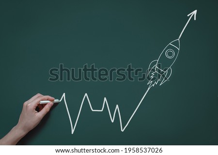 hand draws in chalk on a blackboard a graph with a flying rocket, the concept of success, a new idea, development in business, future profit
