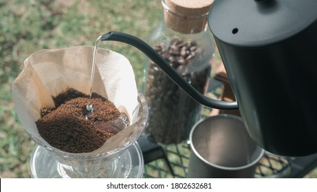 Hand drip coffee in the camp, A man pouring water on coffee ground with filter.Drip coffee and camping.