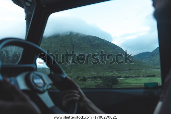 Hand driving\
car road trip Scotland mountains\
