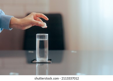 
Hand Dropping An Effervescent Pill Of Calcium And Magnesium In Water. Medical Beverage Made From Soluble Fizzy Vitamin Tablet 
