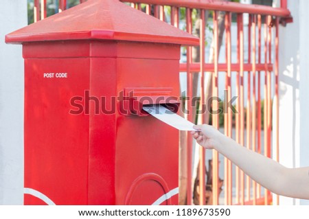 Hand dropping mail into red mailbox sending  wish to other people