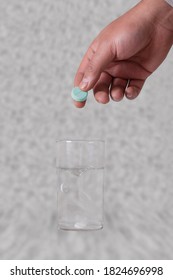 Hand Dropping Pills In A Glass Of Water