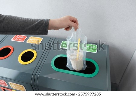 Hand dropping plastic trash or coffee bottle into trash can