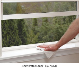 Hand dusting a window sill to reduce allergens in the home.