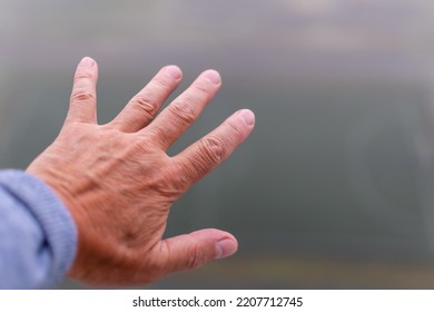 Hand of elderly man close-up on blurred background of fog. Focus in the center of image - Shutterstock ID 2207712745