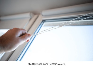 The hand of an elderly man opens a window in the apartment. Pull the rope of the roller curtain.Close the windows in the apartment. - Powered by Shutterstock