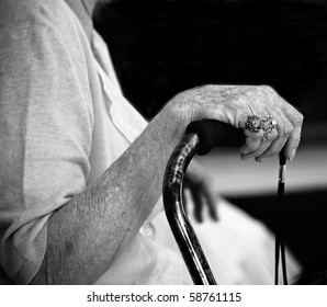 Hand of elderly woman with beautiful rings holding walking stick (black and white version)